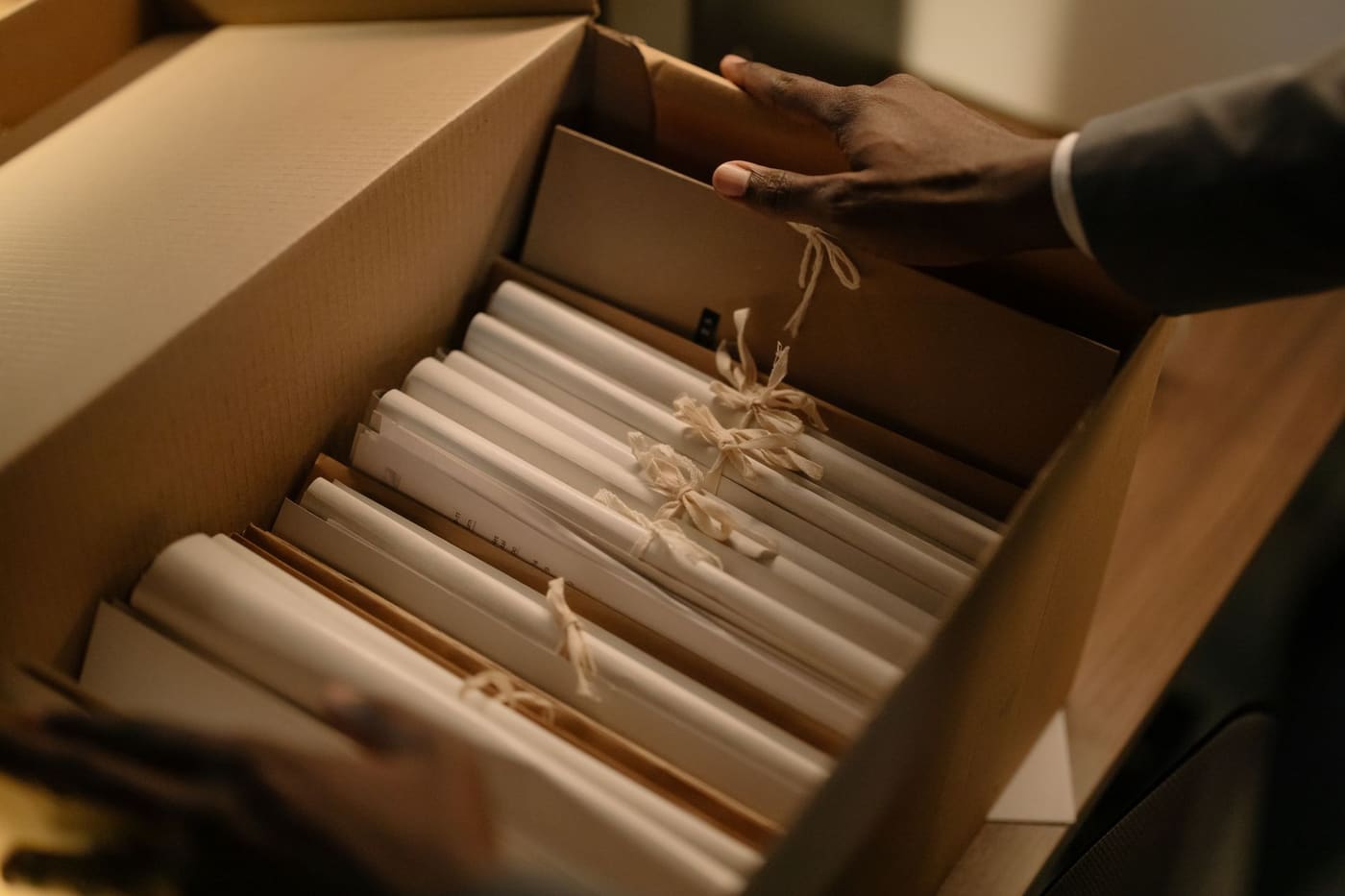 Hands sorting folders and papers inside a cardboard box